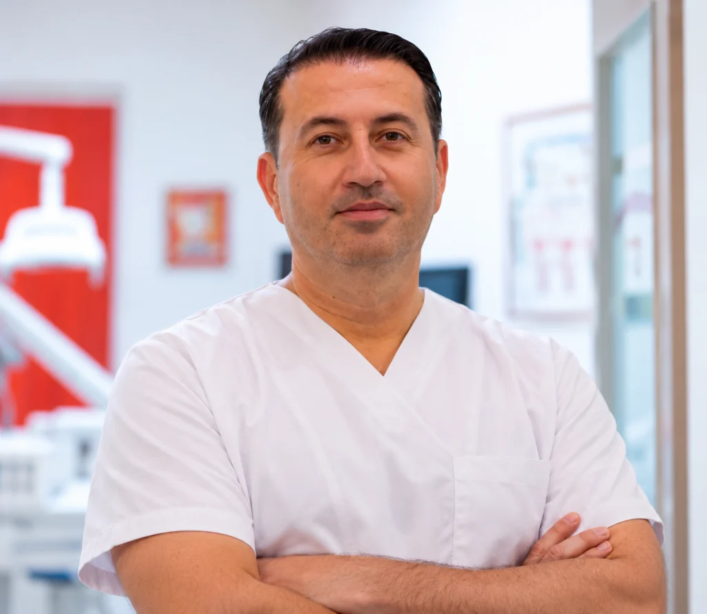 Dr. Gazmend Spahiu, Assistenzzahnarzt, mit verschränkten Armen im Behandlungszimmer